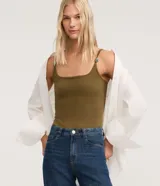 Body femenino ajustado, sin mangas, color verde oliva, con escote cuadrado y breteles finos dobles adornados con piezas decorativas. El tejido es texturizado.