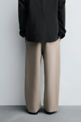 Pantalón de corte relajado en color verde militar, con diseño de pliegues frontales, bolsillos laterales y cierre de cremallera con botón.