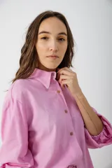 Camisa blanca con estampado de hojas en tonos beige y verde, cuello camisero, mangas largas con lazos en los puños y botones de madera.