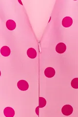 Top rosado con estampado de lunares fucsia, de cuello redondo y mangas cortas abullonadas con pliegues. Cuenta con escote en V en la espalda y cierre con cremallera oculta.