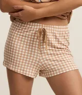 Conjunto de pijama compuesto por una remera de manga corta color beige con estampado frontal de Snoopy y un short a cuadros vichy con cintura elástica.