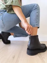 Botas negras de cuero con caña baja, cierre lateral con cremallera y suela track.