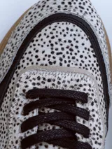 Championes urbanos de diseño exclusivo con paneles en cuero negro y textil estampado con motivo animal print de puntos. Presenta una suela de plataforma en tono marrón con relieve dentado y detalles en cuero beige en el talón.