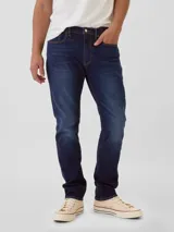 Pantalón de jean corte athletic slim, color azul oscuro con efecto lavado, de tiro medio y cierre frontal con botón y cremallera.