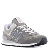 Championes urbanos New Balance modelo 574, color gris con detalles en blanco y negro. Confeccionados en una combinación de gamuza y malla, cuentan con el logo N característico en los laterales y entresuela con tecnología ENCAP para mayor amortiguación.