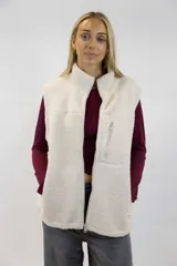 Chaleco de corderito color blanco off-white, con cuello alto, cierre frontal y bolsillo con cierre en el pecho.