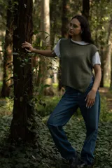 Chaleco corto de punto color verde oliva, con cuello amplio y aberturas laterales con lazos para ajustar.