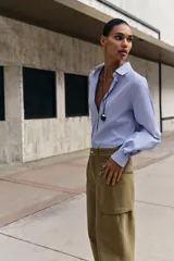 Camisa de manga larga con cuello solapa, cierre frontal con botones y bajo asimétrico, con estampado de rayas verticales.