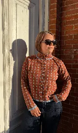 Cardigan reversible de punto con estampado de rombos pequeños, cuello alto y cierre frontal completo con botones. Presenta detalles de ribetes en color contrastante en cuello, puños y cartera de botones.