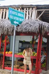 Vestido corto de tejido de punto color beige, con escote profundo tipo halter y falda con volados en el frente.