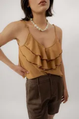 Musculosa negra con escote en V, breteles finos regulables y doble volado frontal con pespuntes.