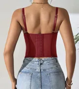 Corset de encaje con transparencias, escote corazón y tirantes finos ajustables. Presenta varillas verticales que estructuran la prenda y detalle de encaje festoneado en el borde superior.
