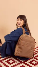 Mochila negra de tela impermeable con detalles en cuero sintético color marrón. Tiene un bolsillo grande frontal con broche, asas ajustables y faja para carry on.