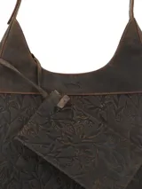 Cartera hobo de cuero color marrón, con diseño grabado de hojas en la parte inferior, asa ajustable y cierre superior.