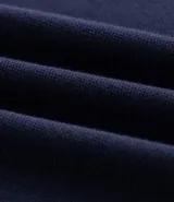 Chomba azul marino de corte boxy y manga corta, confeccionada en tejido piquet de algodón. Cuenta con cuello polo y ribetes en las mangas de color beige contrastante, además de una botonera frontal corta.