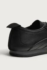 Zapatillas de estilo retro para hombre, de color negro, con diseño monocolor y cordones a tono. Presentan una parte superior con combinación de piezas y suela dentada.