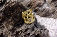 Anillo ancho de diseño orgánico y calado, con apariencia de red o magma solidificado.