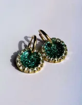 Aros colgantes dorados con dije circular de resina color turquesa, bordeado con strass. El arito es de acero quirúrgico.
