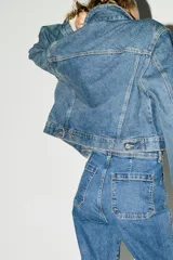 Jean de tiro alto con corte acampanado desde la rodilla. Presenta bolsillos tipo parche en la parte frontal y cierre con botón metálico.