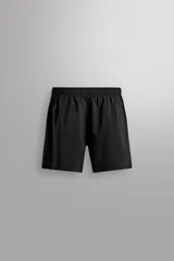 Pantalones cortos deportivos color marrón rojizo, confeccionados en tejido técnico ligero y elástico. Presentan cintura elástica ajustable con cordón interior, bolsillos frontales y un bolsillo trasero con cierre de cremallera. Los laterales tienen perforaciones para transpirabilidad y aberturas laterales en el bajo.