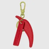 Charm para bolso o mochila con diseño de ají, confeccionado en cuero sintético color rojo con textura granulada. Incluye una tira colgante con el logo de la marca grabado y un mosquetón metálico en color verde oliva.