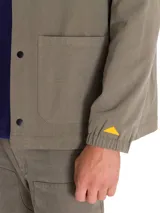 Chaqueta tipo coach de color verde oliva, con cierre frontal a presión, cuello camisero, puños elásticos y múltiples bolsillos frontales. Incluye etiqueta con logo de la marca en el pecho.