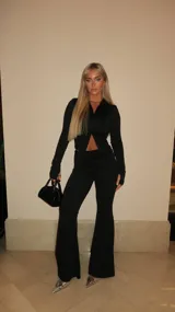 Conjunto negro compuesto por un top de manga larga con cierre frontal y abertura tipo cut-out, y un pantalón de corte acampanado. Confeccionado en tela elástica que se ajusta al cuerpo.