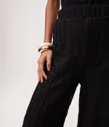 Pantalón de tricot negro con corte wide leg, transparencia delicada y bordado abstracto en relieve. Cuenta con cintura elástica y caída fluida.