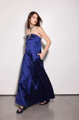 Vestido largo azul con escote strapless, corte suelto y fluido, confeccionado en tafeta con efecto tornasolado, y bolsillos ocultos en los laterales.
