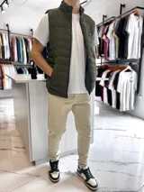 Chaleco puffer de nylon color verde militar, con cuello alto, cierre frontal y capucha desmontable. Presenta un parche circular con la inscripción "Turk" en el pecho.