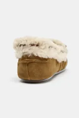 Mocasín plano tipo náutico confeccionado en serraje color tostado, con interior y borde superior forrados en tejido efecto borreguito. Presenta detalle fruncido en la puntera redonda y borlas decorativas en la parte frontal.