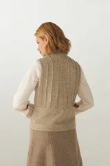 Chaleco corto entallado de lana fina sin teñir, color marrón claro jaspeado, con cierre frontal y alforzas verticales en delantera y espalda.