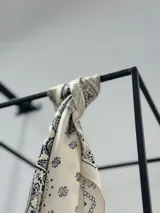 Pañuelo cuadrado tipo bandana de tela tipo seda color manteca con estampado de cachemir en azul marino.