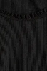 Top corto negro de punto acanalado, de manga corta y ajuste entallado. Presenta ribete de encaje festoneado en el escote redondo y en los bordes de las mangas.