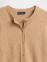 Saco de punto fino color marfil, con cuello redondo, cierre frontal con botones y mangas largas.