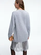 Sweater de tejido de punto color beige, con cuello redondo y mangas largas. Presenta un diseño de largo extendido con un delicado aplique de encaje en el ruedo inferior.