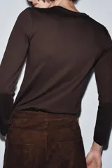 Camiseta de manga larga confeccionada en tejido de punto interlock elástico y flexible, con cuello redondo y bajo recto.