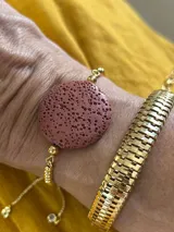 Pulsera dorada con tres piedras volcánicas negras y cierre corredizo.