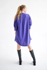 Vestido camisero corto color violeta con bordados florales en los hombros, mangas 3/4 abullonadas con puños elásticos y cierre frontal con botones.