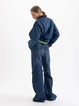 Pantalón de jean estilo cargo con corte holgado y tiro medio. Presenta múltiples bolsillos laterales con solapa, costuras reforzadas y un acabado de lavado azul clásico.