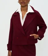 Abrigo corto tipo blazer de color bordó con estampa de espiga, cuello con solapas, cierre cruzado con dos botones y bolsillos ribeteados.
