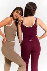 Conjunto deportivo compuesto por una musculosa con escote redondo y vivos blancos, y un pantalón de corte recto con cintura cruzada en V. Ambas prendas son de color habano y presentan el logo bk. estampado en blanco.