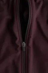 Campera deportiva corta color bordó con tecnología SoftMove y DryMove, de corte ajustado, cuello alto, cierre frontal y mangas largas con abertura para el pulgar.