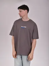 Remera color verde petroleo, de manga corta y corte oversize, con estampa en el pecho izquierdo que dice 'Noble Origins' junto a un diseño floral.