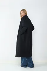 Tapado largo de corte oversize con cuello solapa y cierre frontal, confeccionado en tejido con textura suave y estructura definida.