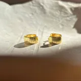 Par de aros dorados tipo cuff con textura acanalada.