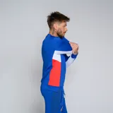 Buzo deportivo de manga larga, color azul, con cuello redondo y detalles en rojo y blanco en los laterales. Presenta el logo de Umbro y el escudo del Club Nacional de Football en el pecho.