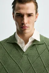 Polo regular fit verde de punto de algodón, con cuello solapa, abertura frontal y diseño de calados geométricos en rombos.