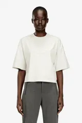Camiseta corta Diesel T-Cropyn-S1 de color blanco, corte holgado con hombros caídos y mangas cortas. Presenta un estampado sutil en relieve en forma de collar de cadena alrededor del cuello.