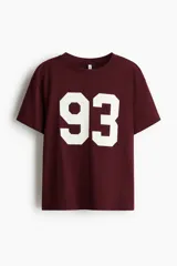 Remera de manga corta color bordó, con cuello redondo y corte holgado. Estampado grande con el número "93" en color blanco en el frente.